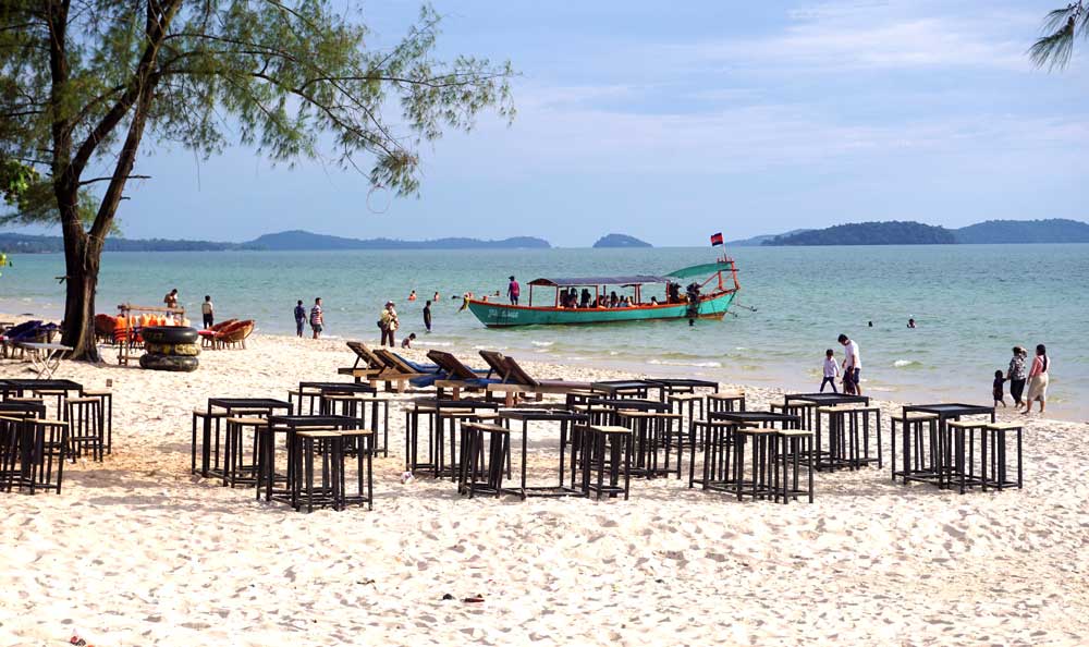 Empty beachside restaurants. Small groups of tourists board a boat for an island day-trip. Chinese expansion in Sihanoukville has led to a decline in other tourists, so local vendors and businesses are struggling. Photo: RFA
