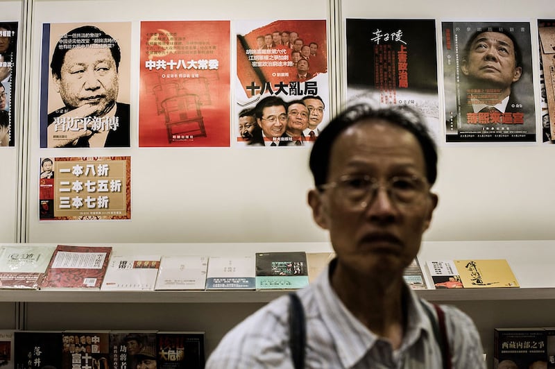 2012年7月18日,一名男子在香港书展上走过展示中国政治书籍的海报。(法新社)