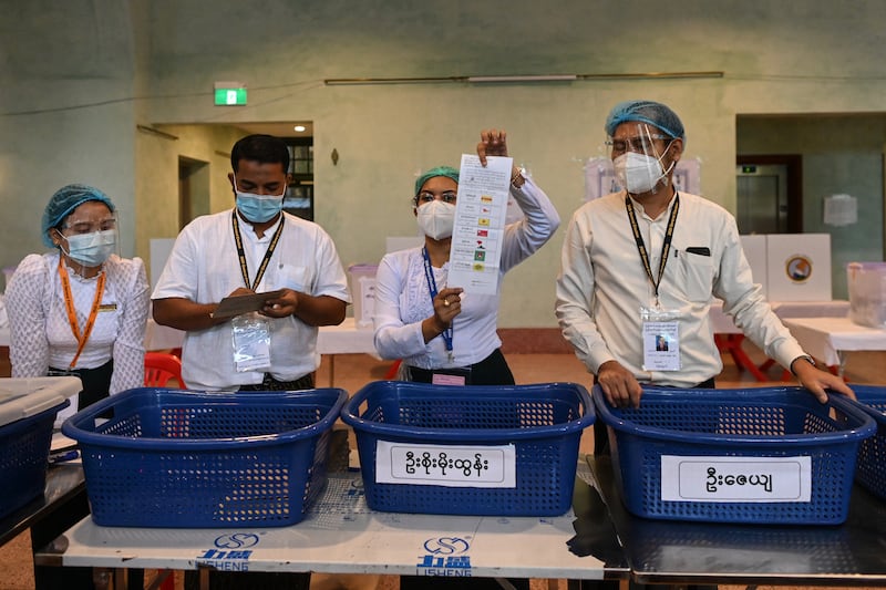 Election officials display a ballot as they count votes after polls closed in Yangon, Nov. 8, 2020.