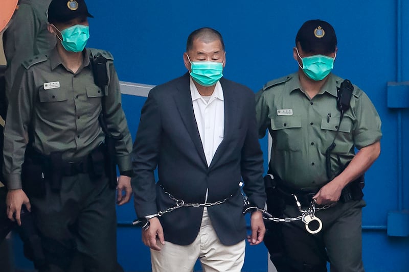 Jimmy Lai, center, who founded the Apple Daily tabloid, is escorted by Correctional Services officers to get on a prison van before appearing in a court, in Hong Kong on Dec. 12, 2020.