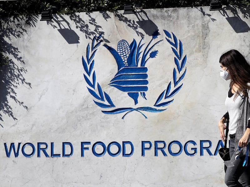 A woman walks past a sign at the entrance of the United Nations World Food Program headquarters in Rome, Oct. 9, 2020