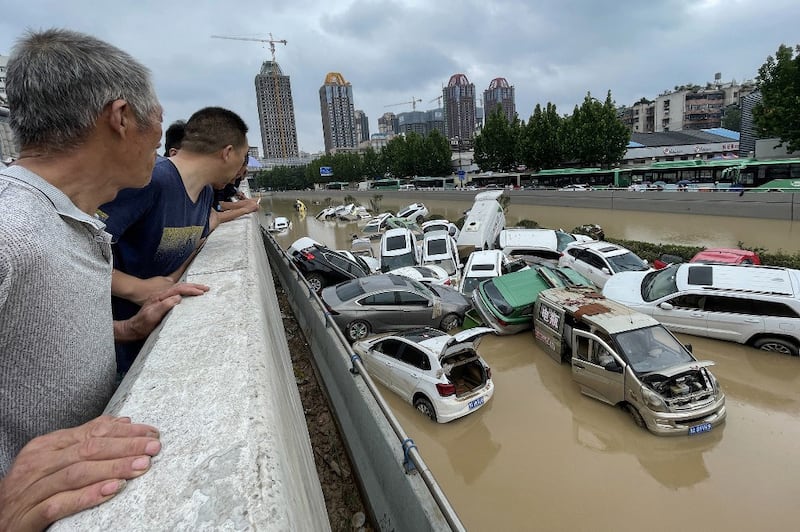 People look out at cars sitting in floodwaters after heavy rains hit the city of Zhengzhou in China's central Henan province, July 21, 2021. Credit AFP