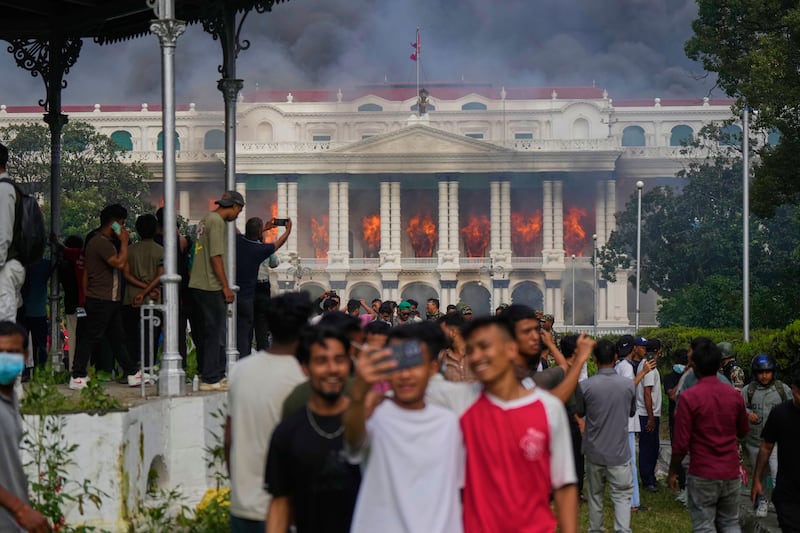 Protesters take selfies and celebrate at the Singha Durbar, the seat of Nepal's government's various ministries and offices, after it was set on fire during a protest against social media ban and corruption in Kathmandu, Nepal, Sept. 9, 2025.