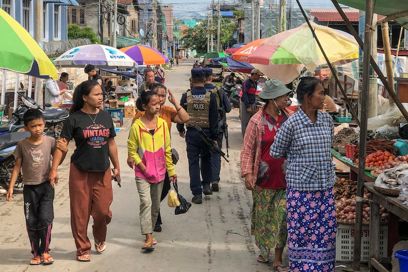 Armed police walking past people at a market area in Lashio in Myanmar's northern Shan state on Sept. 10, 2024, after the Myanmar National Democratic Alliance Army (MNDAA) seized the town from Myanmar's military in August. (AFP Photo)