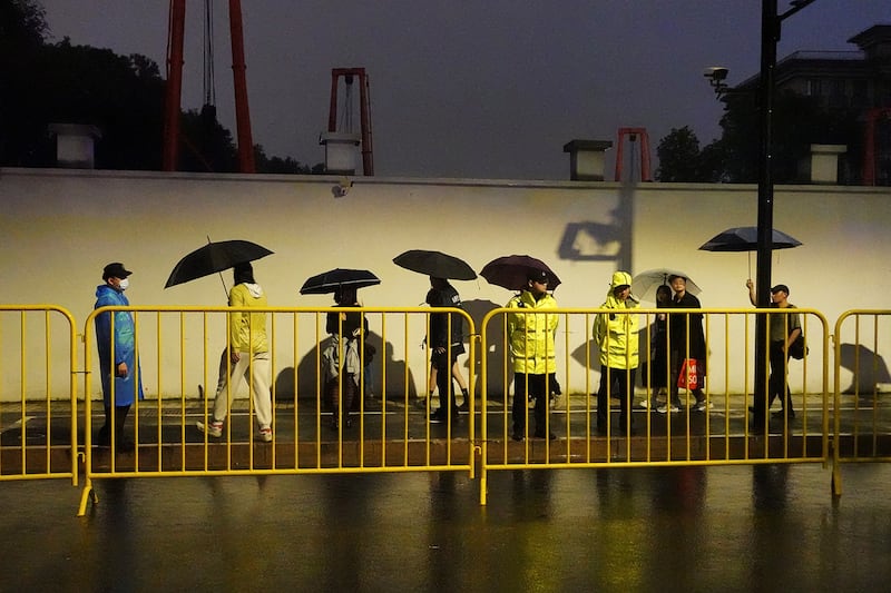 Police officers keep watch near barricades set up along Julu Road where people in Halloween costumes gathered the year before in Shanghai, Oct. 26, 2024.